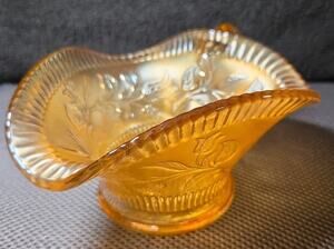 Iridescent marigold carnival glass handled bowl with floral pattern